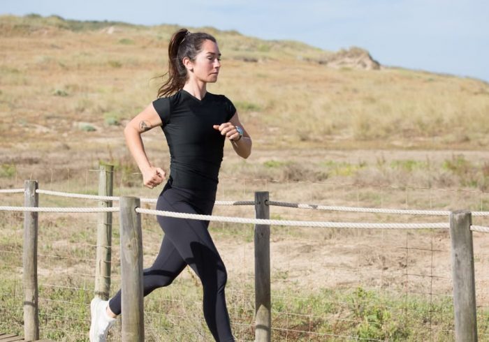 Woman jogging on a sunny day on a wooden path in Portugal, embracing a healthy lifestyle.